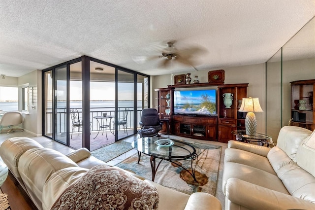 living room featuring a textured ceiling, a wall of windows, and ceiling fan