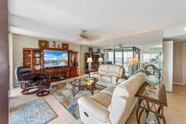 living room with a textured ceiling, ceiling fan, and light tile patterned flooring