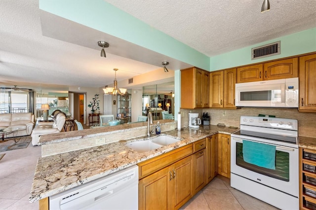 kitchen featuring a textured ceiling, white appliances, kitchen peninsula, and an inviting chandelier