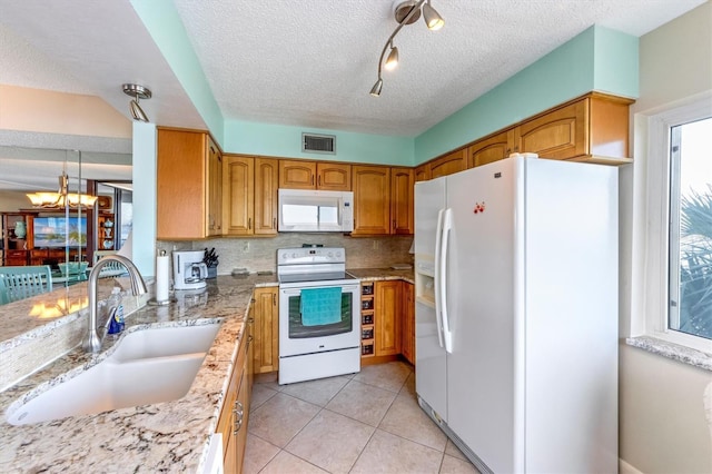 kitchen featuring white appliances, sink, decorative backsplash, a textured ceiling, and light stone counters