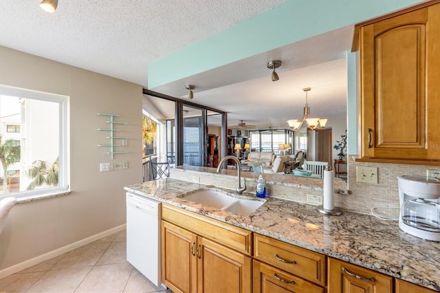 kitchen with white dishwasher, an inviting chandelier, a healthy amount of sunlight, and sink