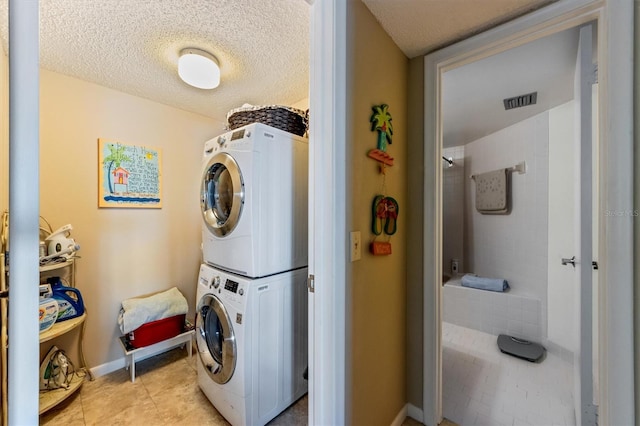 washroom featuring a textured ceiling, light tile patterned floors, and stacked washer and clothes dryer