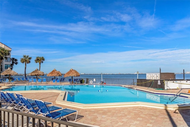 view of pool featuring a water view and a patio