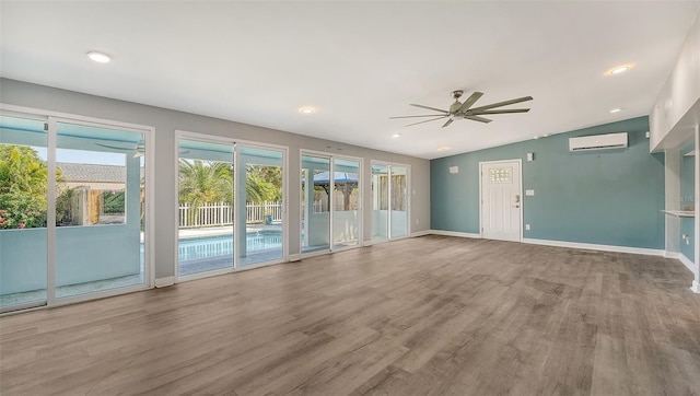 unfurnished living room featuring hardwood / wood-style flooring, vaulted ceiling, a wall mounted AC, and ceiling fan