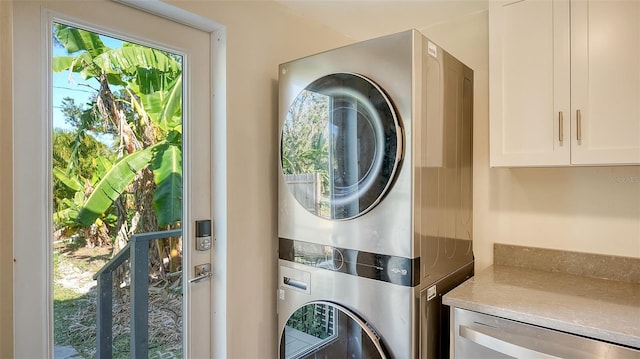 clothes washing area with cabinets and stacked washer and clothes dryer