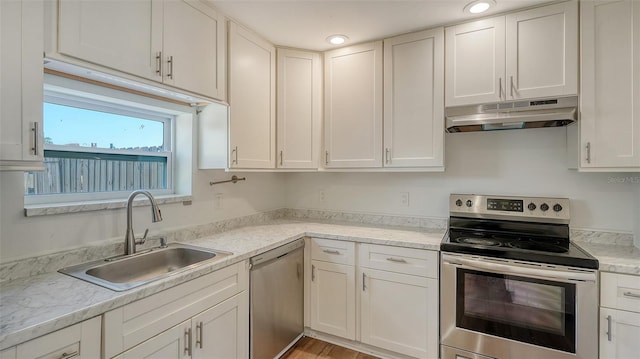 kitchen featuring sink, light stone countertops, light hardwood / wood-style floors, white cabinetry, and stainless steel appliances