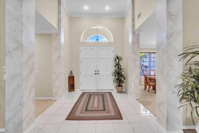 tiled foyer entrance featuring baseboards, visible vents, and ornamental molding