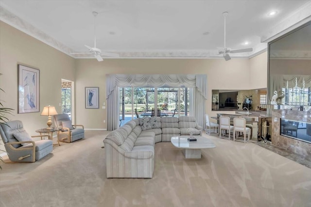 carpeted living area with crown molding, baseboards, a towering ceiling, and ceiling fan