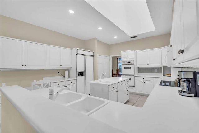 kitchen with visible vents, light countertops, white cabinets, white appliances, and a sink