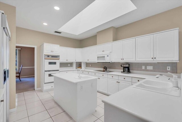 kitchen with tasteful backsplash, white appliances, a skylight, and a sink