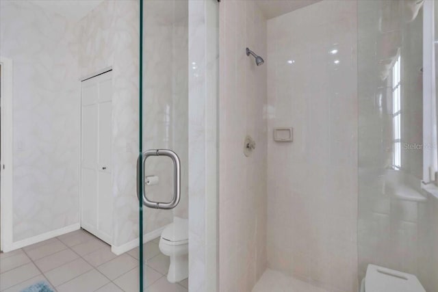 bathroom with toilet, tile patterned flooring, and a tile shower