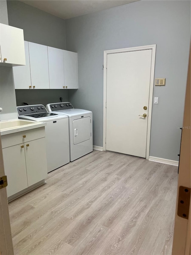 laundry area with washer and clothes dryer, cabinet space, baseboards, and light wood-style floors