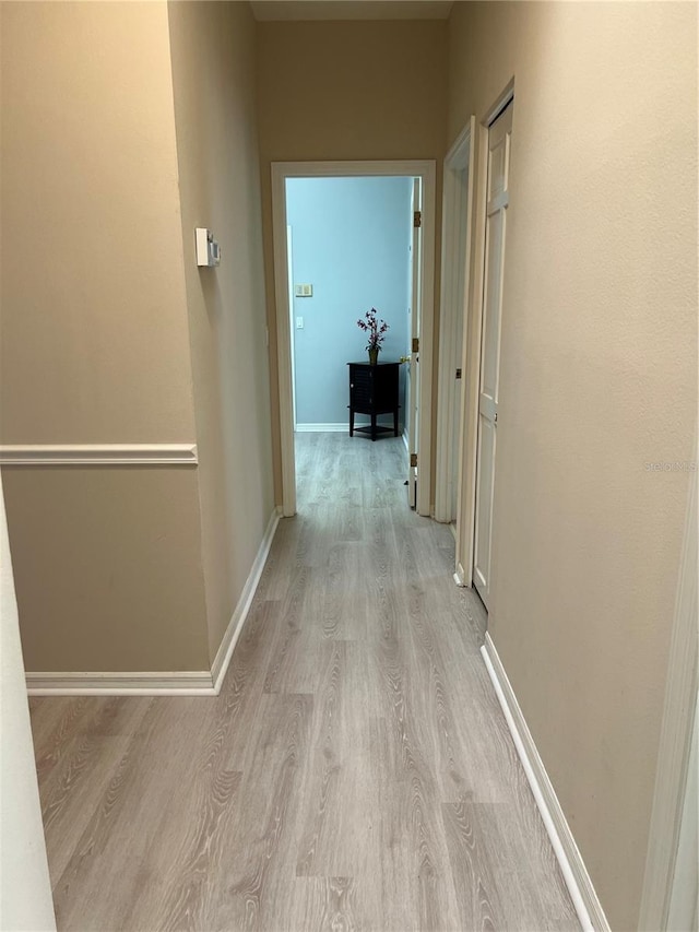 corridor featuring light wood finished floors and baseboards