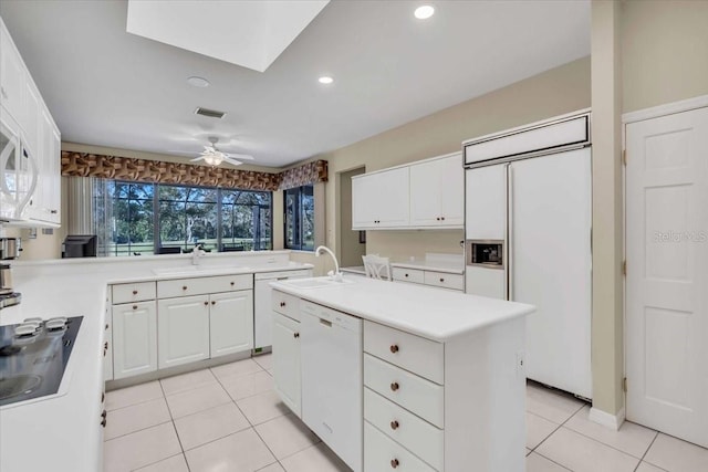 kitchen with white appliances, white cabinets, light countertops, and a sink