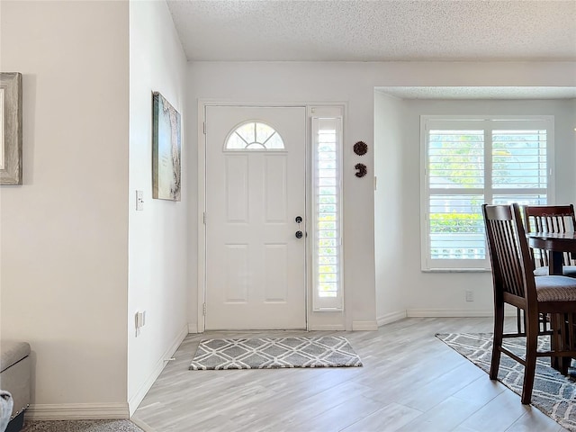 foyer with light wood-type flooring and a textured ceiling