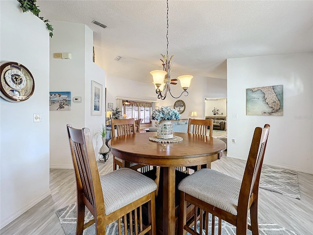 dining room featuring a textured ceiling, light hardwood / wood-style flooring, and a notable chandelier