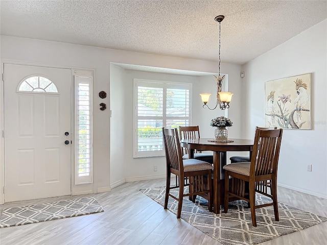 dining area featuring a wealth of natural light, hardwood / wood-style floors, a textured ceiling, and a notable chandelier