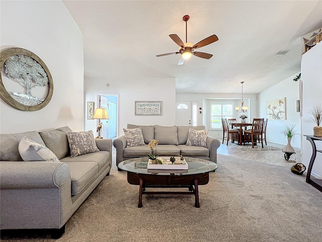 carpeted living room with a textured ceiling and ceiling fan with notable chandelier