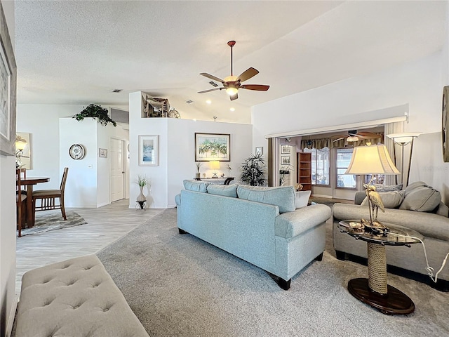 living room featuring ceiling fan, light hardwood / wood-style flooring, a textured ceiling, and vaulted ceiling