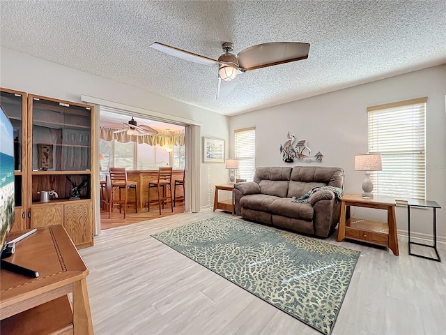 living room with ceiling fan, wood-type flooring, and a textured ceiling