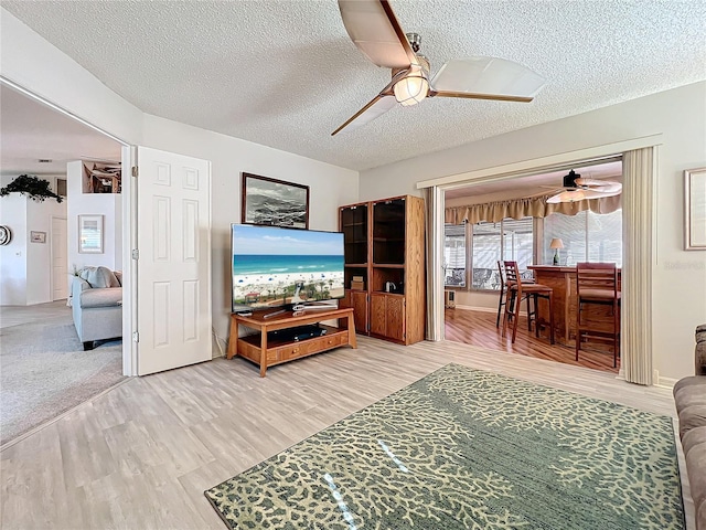 living room featuring hardwood / wood-style floors, a textured ceiling, and ceiling fan