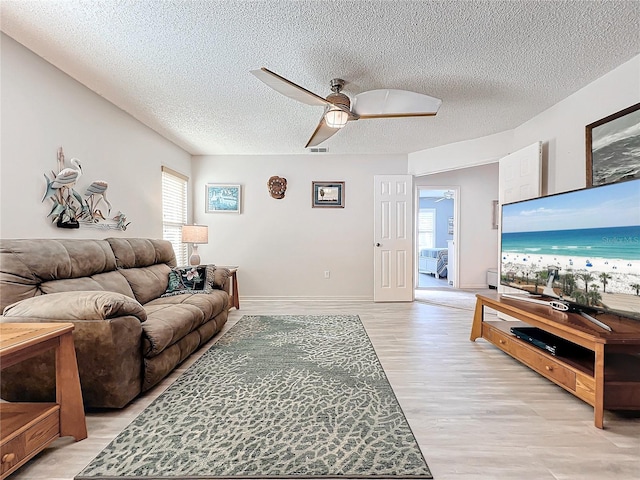 living room with ceiling fan, light hardwood / wood-style flooring, and a textured ceiling