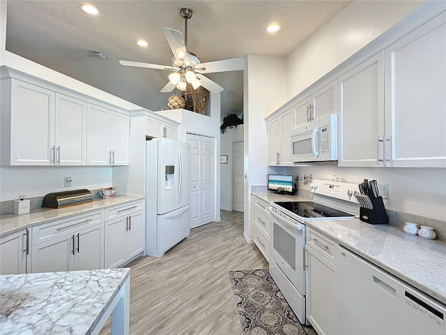 kitchen featuring white cabinetry, light stone countertops, and white appliances