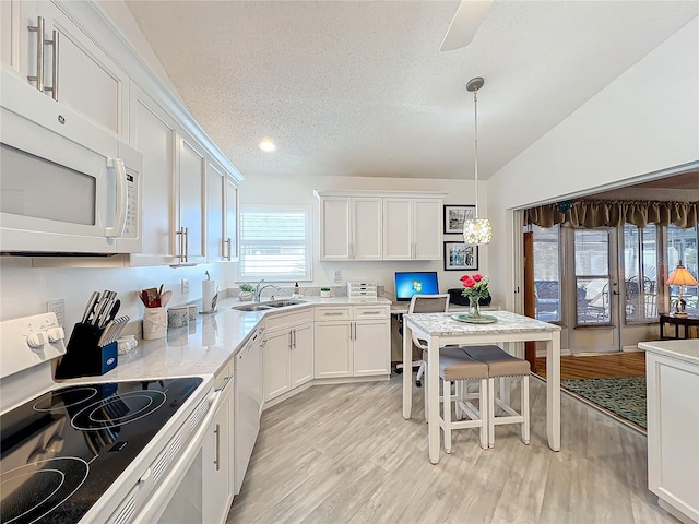 kitchen featuring white appliances, sink, vaulted ceiling, a textured ceiling, and white cabinetry