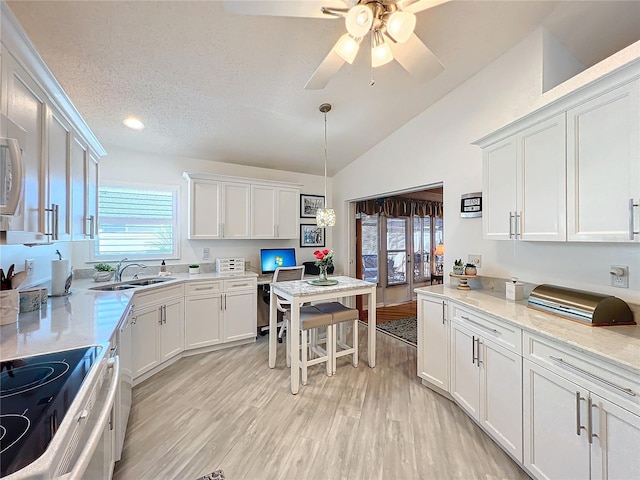 kitchen with pendant lighting, lofted ceiling, light wood-type flooring, a textured ceiling, and white cabinetry