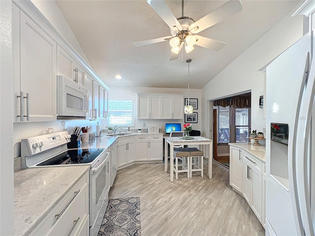 kitchen with light hardwood / wood-style floors, a textured ceiling, lofted ceiling, white appliances, and white cabinets