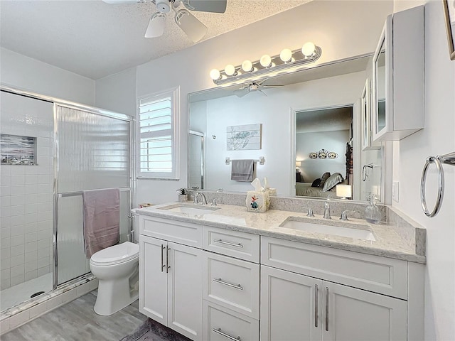 bathroom featuring hardwood / wood-style floors, a shower with shower door, a textured ceiling, and toilet