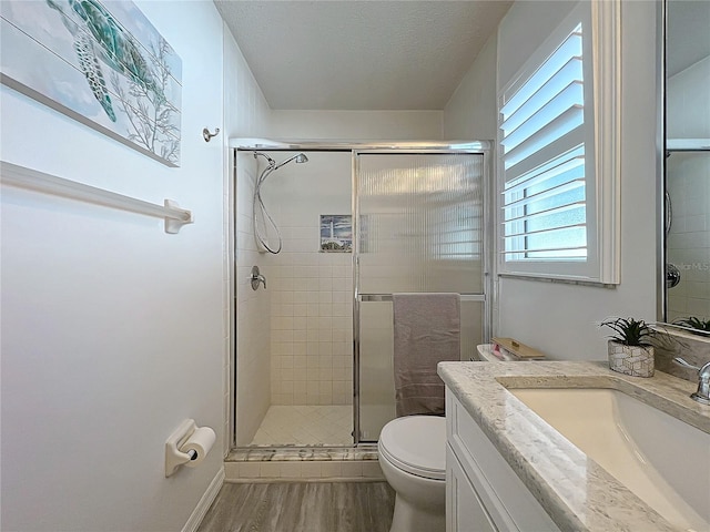 bathroom featuring walk in shower, hardwood / wood-style floors, a textured ceiling, toilet, and vanity