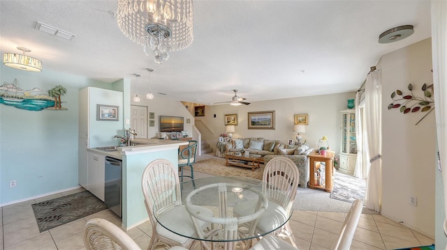 dining space featuring light tile patterned floors, ceiling fan with notable chandelier, a textured ceiling, and sink