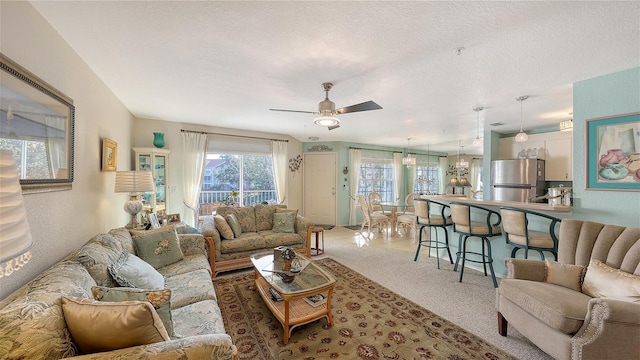 living room with carpet flooring, ceiling fan, and a textured ceiling