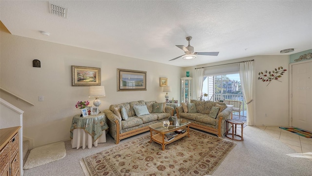 living room with ceiling fan, light colored carpet, and a textured ceiling