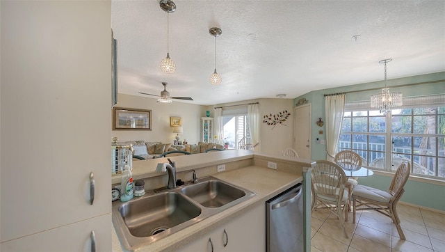 kitchen featuring dishwasher, pendant lighting, ceiling fan with notable chandelier, and sink