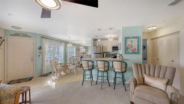 kitchen with white cabinets, ceiling fan, appliances with stainless steel finishes, light colored carpet, and kitchen peninsula