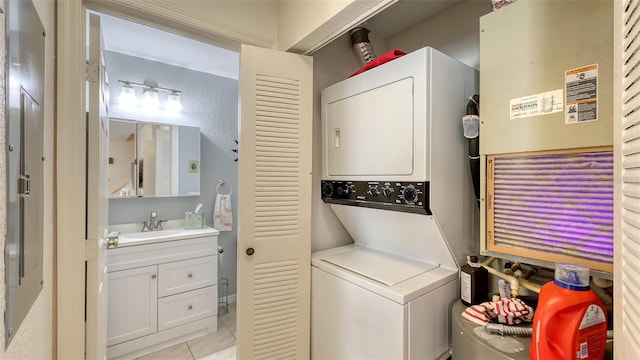 washroom with sink, light tile patterned flooring, and stacked washer and clothes dryer