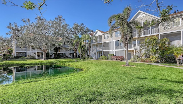 surrounding community with a water view and a lawn