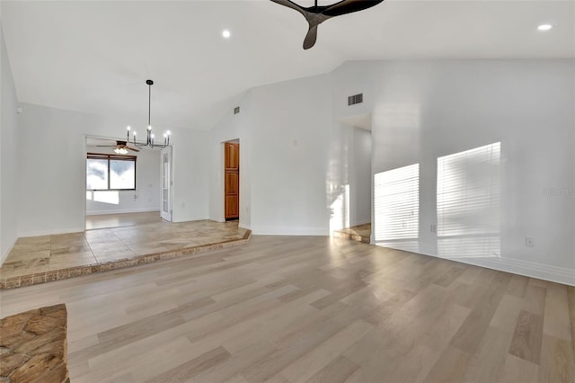 unfurnished living room featuring ceiling fan with notable chandelier, light hardwood / wood-style floors, and vaulted ceiling