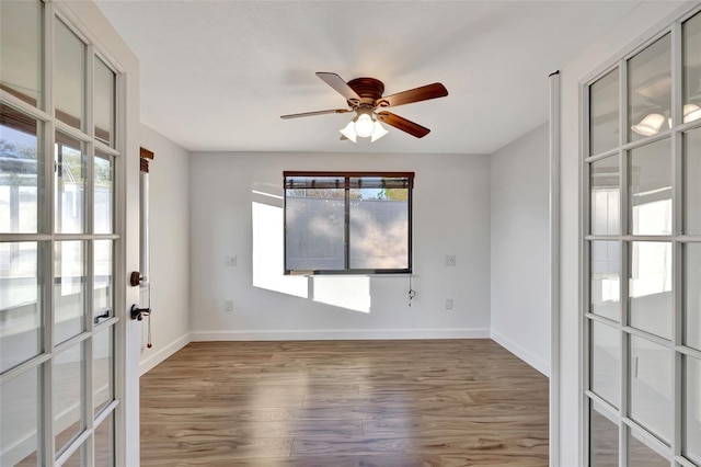 empty room with a wealth of natural light, ceiling fan, and hardwood / wood-style flooring