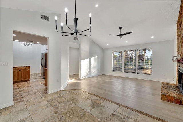 unfurnished living room with vaulted ceiling, a fireplace, and ceiling fan with notable chandelier