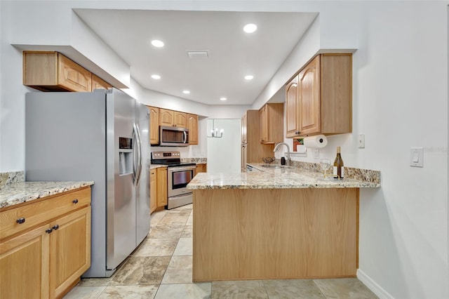 kitchen featuring kitchen peninsula, light stone counters, sink, and appliances with stainless steel finishes