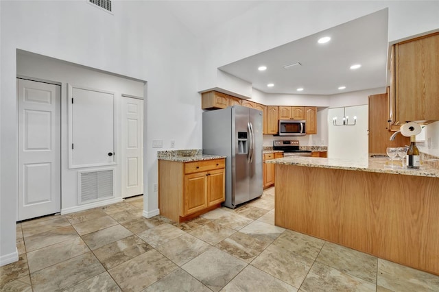 kitchen with kitchen peninsula, light stone countertops, sink, and stainless steel appliances