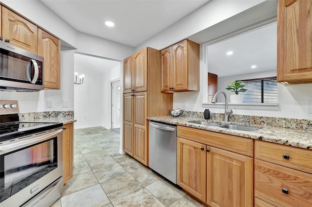 kitchen with a chandelier, light stone counters, sink, and stainless steel appliances