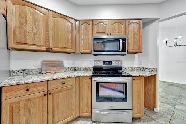 kitchen with a notable chandelier, light stone counters, hanging light fixtures, and appliances with stainless steel finishes