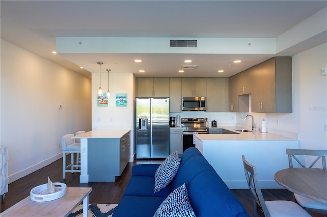 kitchen with pendant lighting, sink, dark hardwood / wood-style floors, appliances with stainless steel finishes, and kitchen peninsula