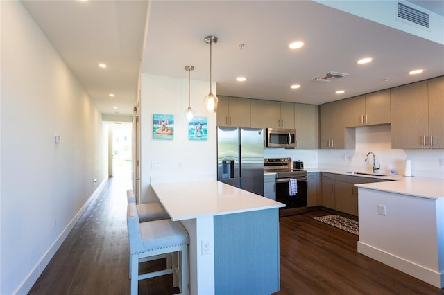 kitchen with sink, dark hardwood / wood-style flooring, decorative light fixtures, a kitchen bar, and appliances with stainless steel finishes