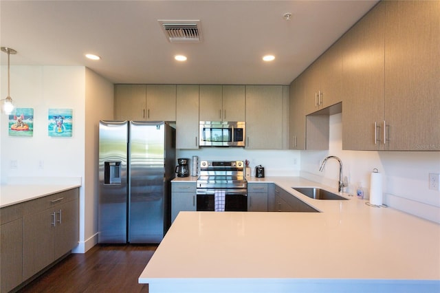 kitchen with sink, dark hardwood / wood-style floors, decorative light fixtures, kitchen peninsula, and stainless steel appliances