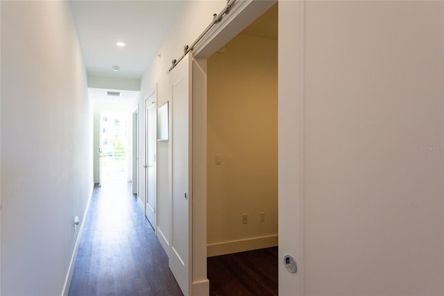 hallway featuring a barn door and dark hardwood / wood-style floors